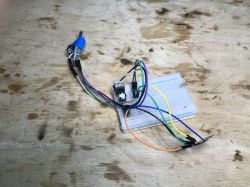 Steckbrett mit USB-zu-UART-Konverter Steckbrett mit angeschlossenen Drähten und USB-zu-UART-Konverter auf einem Holztisch.