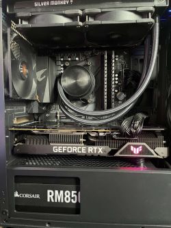 Zbliżenie na wnętrze obudowy komputera z kartą graficzną GeForce RTX, chłodzeniem wodnym i zasilaczem Corsair RM850.