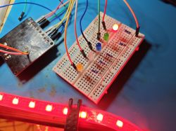 Breadboard with colored LEDs and jumper wires, WS2812B LED strip glowing red