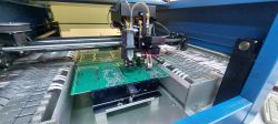 Automat montażowy M60 podczas pracy z płytką PCB w środku urządzenia.