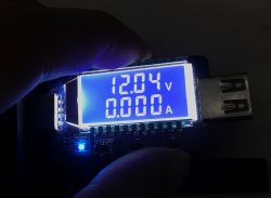 Wyświetlacz testera USB pokazujący napięcie 12.04 V i prąd 0.000 A