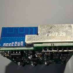 Close-up of an electronic module with pin markings and an antenna.