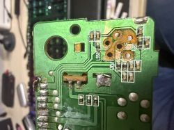 Zbliżenie płytki PCB z odsłoniętymi padami i wyrwanym miejscem po gnieździe, widoczne ścieżki i luty