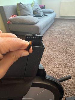 Nahaufnahme einer Hand mit einem Kabelstecker an einem Heimtrainer