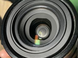 Widok z bliska na obiektyw aparatu Nikon Coolpix 5700 z uszkodzonym elementem wewnętrznym.