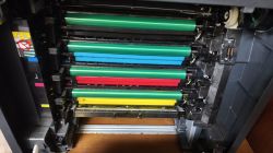 Wnętrze drukarki laserowej z widocznymi czterema wałkami w kolorach CMYK