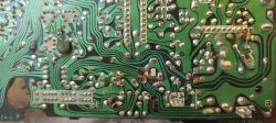 Zbliżenie na spodnią stronę płytki PCB z wieloma lutowaniami i modyfikacjami