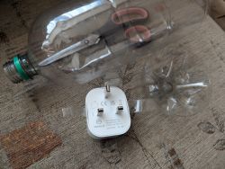 Smart Plug and Disassembly Tools Plastic bottle and smart plug on a carpet.