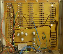 Back of a prototype circuit board with manual wiring and screw terminals