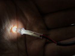 Dioda LED świecąca w ciemności trzymana w dłoni.