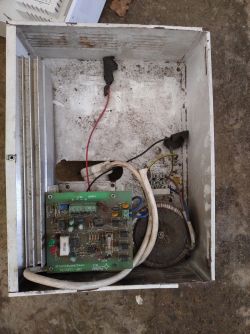 Stare urządzenie elektroniczne z widoczną płytą drukowaną i kablami w środku obudowy.